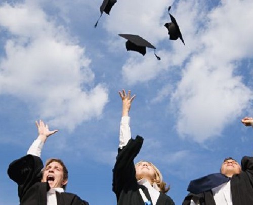 High school graduates throwing their mortarboards in the air